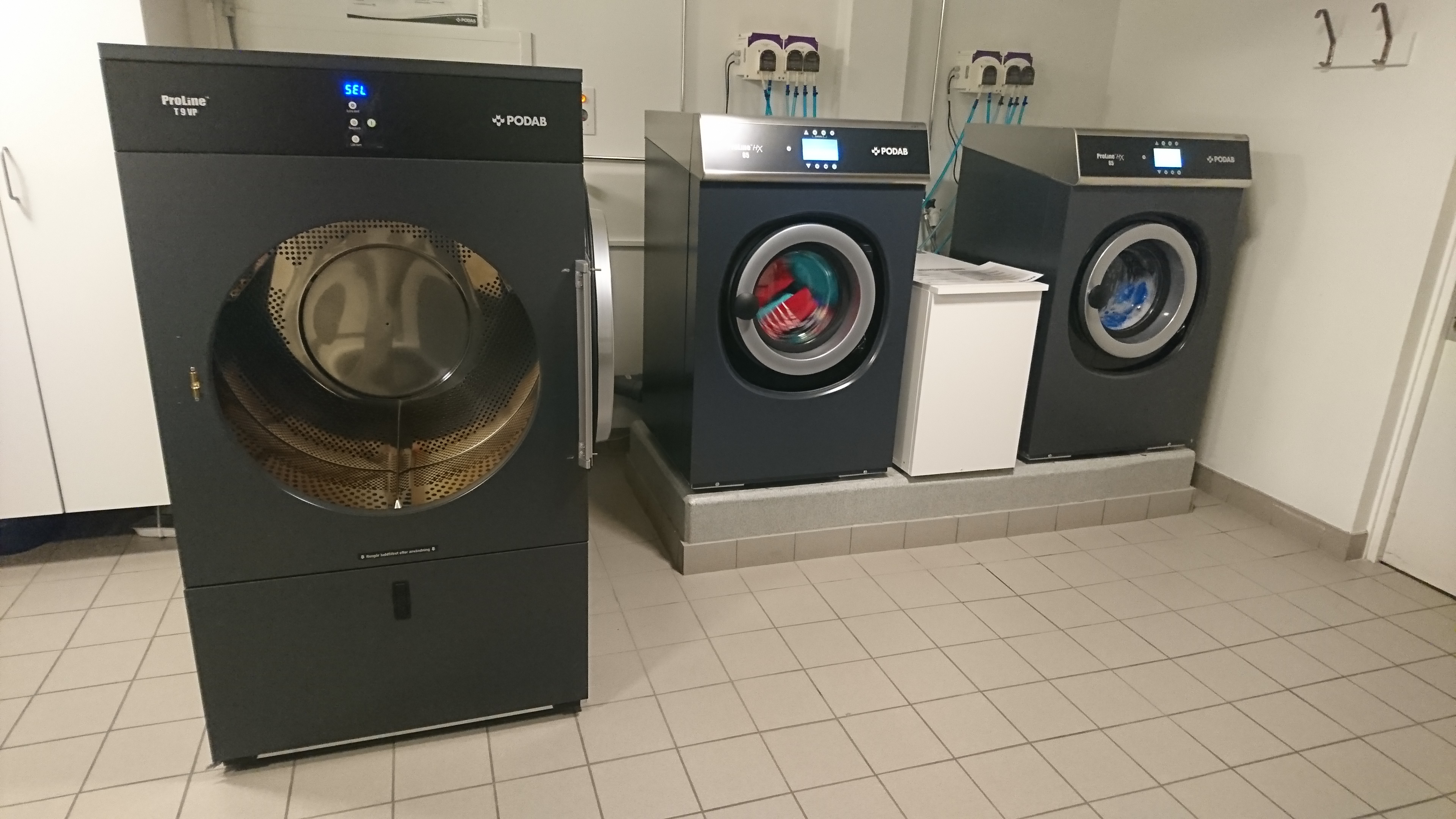 Bild på tvättmaskiner och torktumlare i tvättstuga